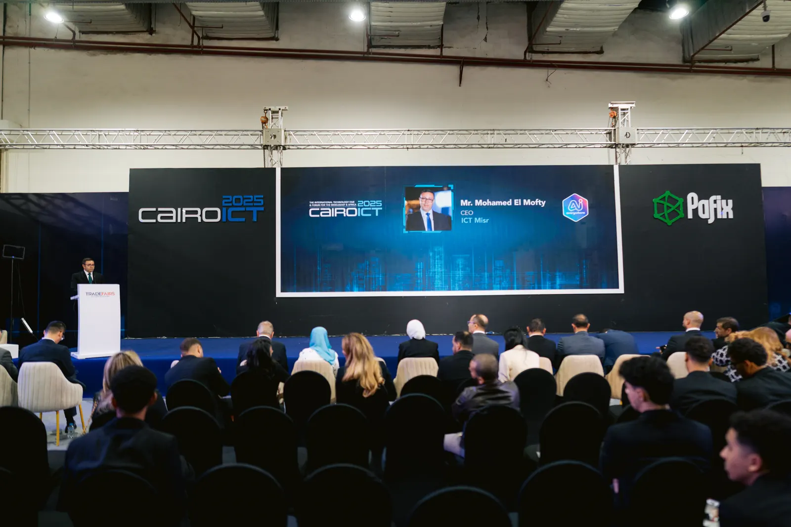 A speaker at the PAFIX 2025 forum, Cairo ICT and PAFIX on the screens behind